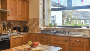 A kitchen with wooden cabinets, a countertop with a fruit bowl, a toaster, and a stove. - 4 bedroom accommodation in Clitheroe (Clitheroe)