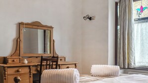 A bedroom with a wooden dresser, a chair, a bed with a plaid blanket, and a window with curtains. - 4 bedroom accommodation in Clitheroe (Clitheroe)
