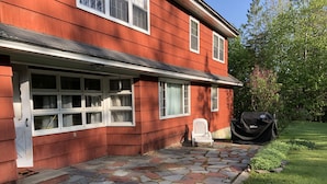 A red house with a stone-paved front porch and a white chair. - The Big House in the Heart of Errol (Errol)