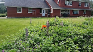 A two-story red house with a sloped roof, a front porch, and a well-maintained lawn. - The Big House in the Heart of Errol (Errol)