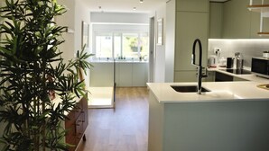 A modern kitchen with a central island, a sink, and a window. - Lisbon, T2 renewed duplex with river view, Beato (Lisboa ciudad)