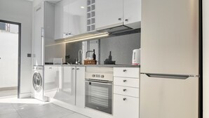 A modern kitchen with white cabinetry, stainless steel appliances, and a built-in oven.