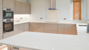 Una cucina moderna con elettrodomestici integrati, un'isola centrale e una finestra con persiane.