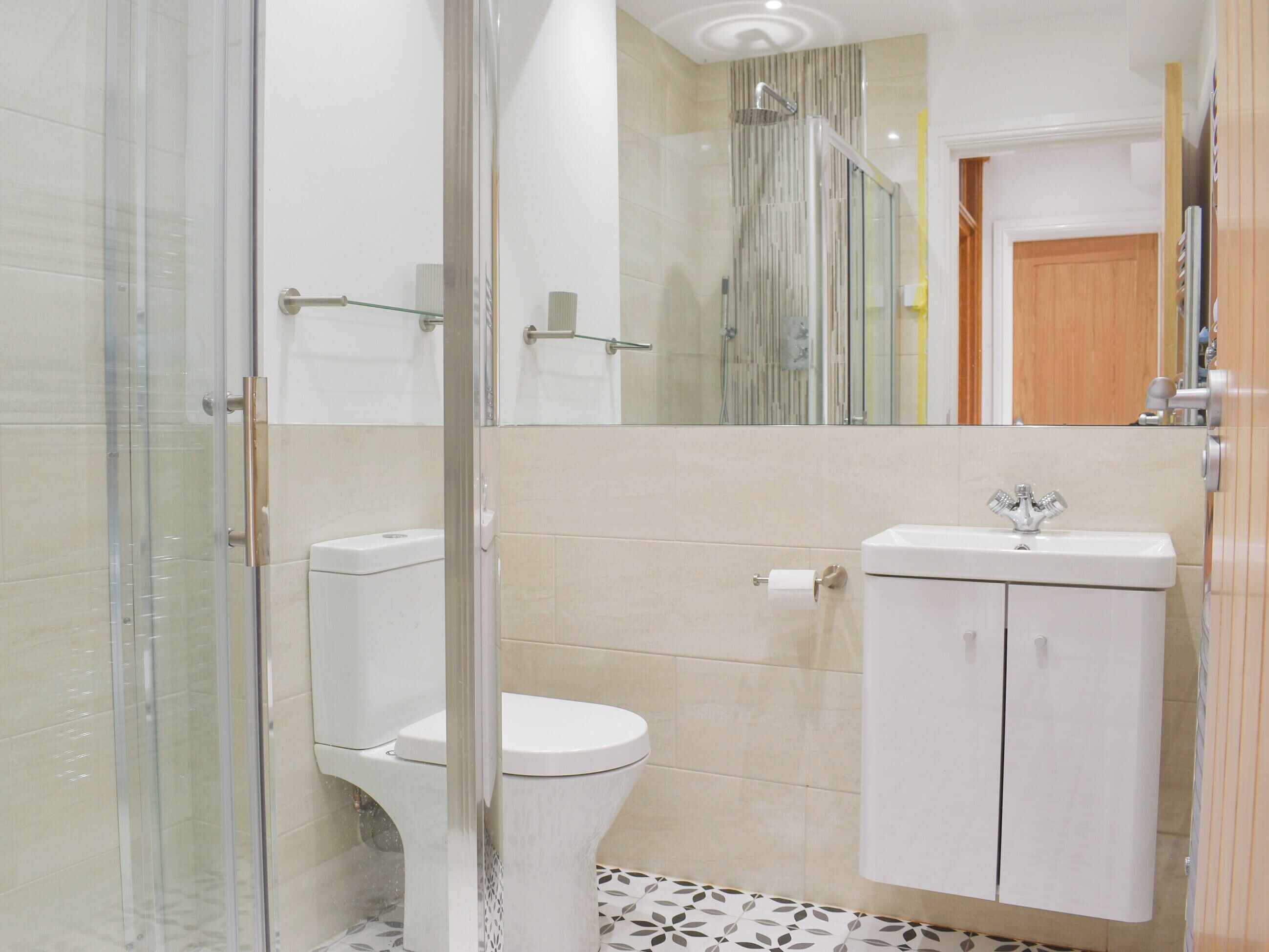 Een moderne badkamer met een douchecabine van glas, een toilet en een wastafel met spiegel.