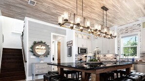A modern kitchen with a central island, white cabinetry, and a decorative chandelier. - August Dates Still Available! 5BR Luxury Home, Pool & Golf Cart • 3 Min to Beach (Miramar Beach)