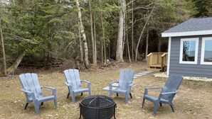 Ein Garten mit vier Adirondack-Stühlen, die um eine Feuerstelle angeordnet sind.