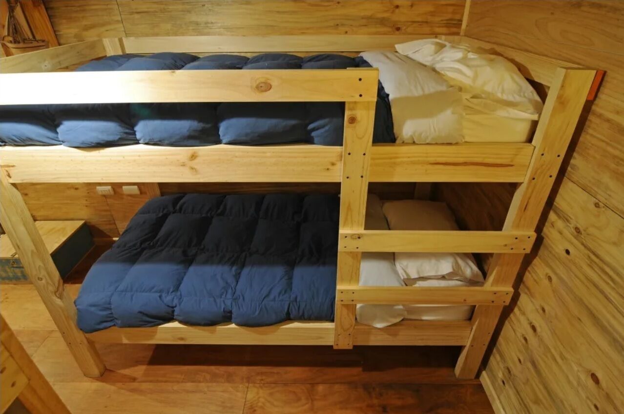 Un lit superposé à trois niveaux, avec des murs en bois et un plancher en bois.