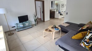 Una sala moderna con sofá, mesa de centro, televisor y un comedor con sillas y una mesa.