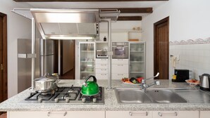A kitchen with a gas stove, a kettle, a sink, and a microwave. - Villa Olivi Pool by Geco Vacation Rentals (Pergine Valdarno)