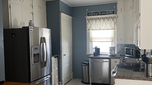 A kitchen with white cabinets, stainless steel appliances, a wooden countertop, and a decorative welcome sign. - House close to Pine Lake and bike trails. (Eldora)