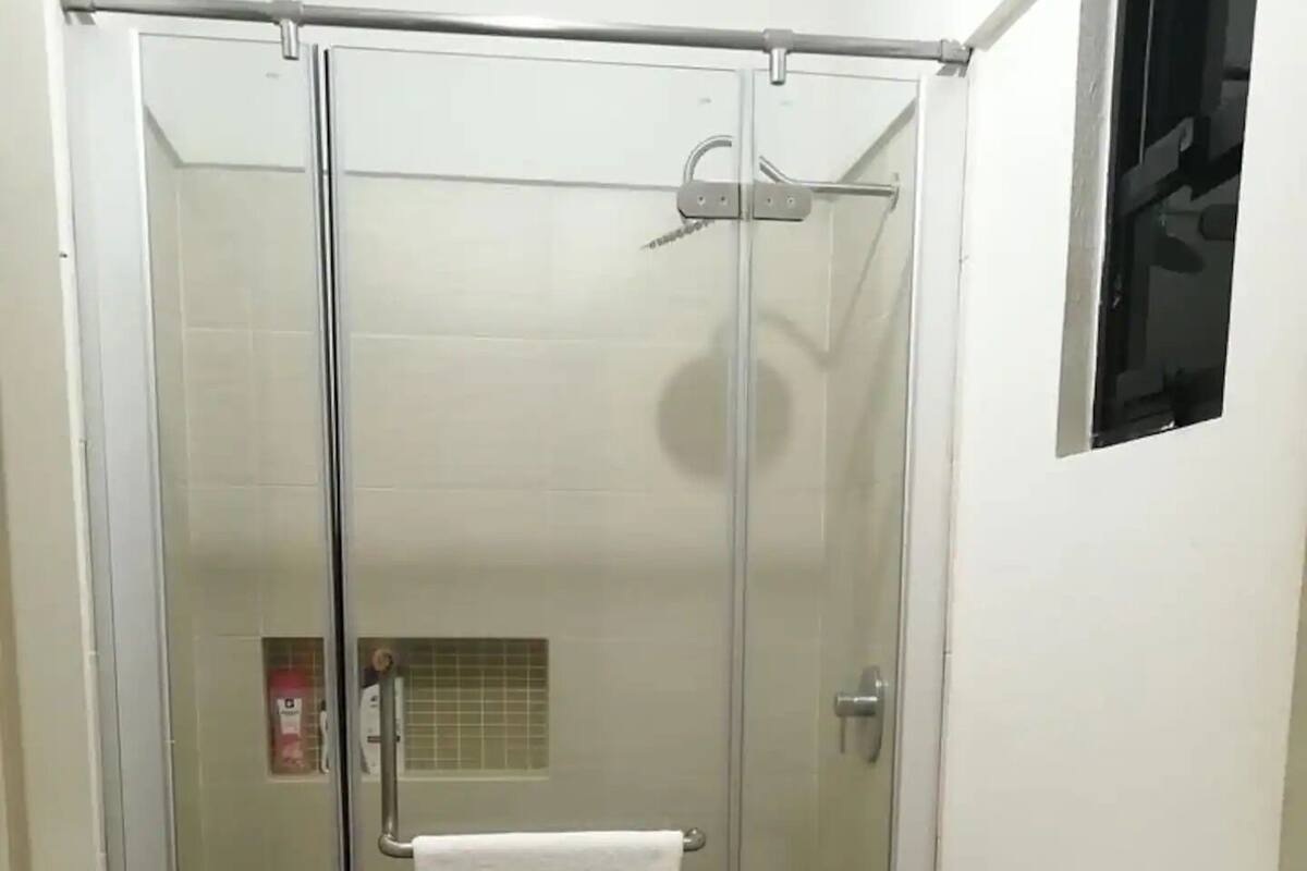 A bathroom with a glass-enclosed shower, a toilet, and a sink.