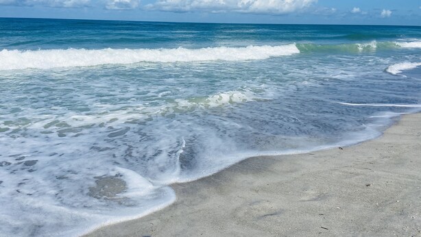 Una playa con olas y cielo despejado.