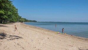 A beach with a clear sky, a sandy shore, and a calm sea. - Stunning Sunrise Shore (Au Gres)