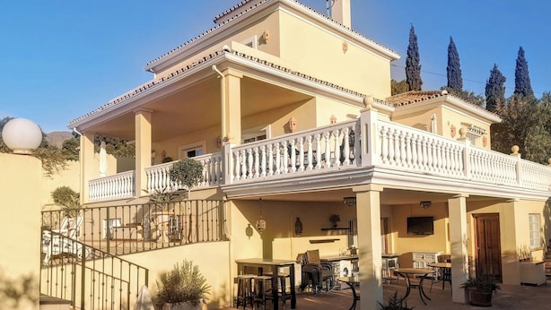 Un bâtiment à deux étages doté d’un balcon et d’un espace extérieur aménagé pour s’asseoir.