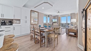 A spacious kitchen with white cabinets, a dining table with chairs, and a large mirror. - Beach Club B1701 | Beachfront | Corner | Resort | Arcade | Pools | Hot Tubs (Gulf Shores)