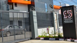 A gated entrance with a sign for '95 Suites & Apartment Boutique Hotel' and contact information.