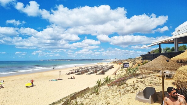 Ein Strand mit Liegestühlen und Sonnenschirmen, ein klarer Himmel und Blick aufs Meer.