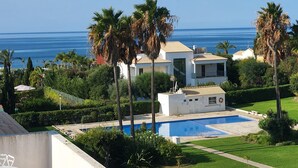 Ein Wohngebiet mit Schwimmbad, Palmen und Blick auf das Meer.