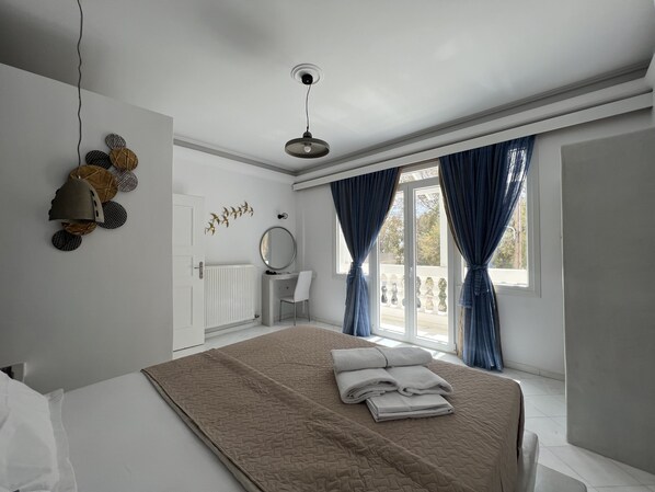 A bedroom with a bed, a bedside table, a mirror, and a window with curtains. - 3 Bedroom House included car rental-Heated Jacuzzi (santorini)