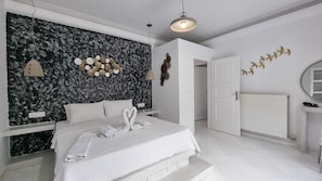 Une chambre à coucher comprenant un lit, des tables de chevet, un luminaire fixé au mur et une porte donnant sur une autre pièce.