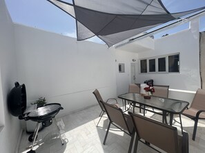 A patio with a grill, table, chairs, and a shaded area. - 3 Bedroom House included car rental-Heated Jacuzzi (santorini)
