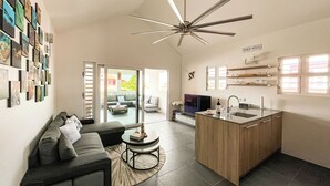 Una cocina moderna con una isla central, un comedor con sofá y una sala de estar con sofá.