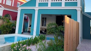 Una casa de dos pisos con un balcón, piscina y cerca de madera.