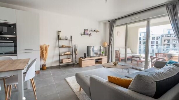 Un salon moderne comprenant un canapé, une table à manger et un coin cuisine.