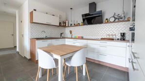 Une cuisine moderne avec des meubles blancs, une table à manger en bois et des chaises blanches.