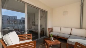 Un balcon avec un canapé, des chaises en bois et une petite table.