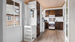 A modern kitchen with white cabinetry, a built-in oven, and a stainless steel refrigerator.