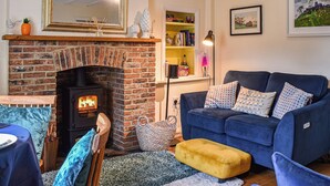 A cozy living room with a brick fireplace, a blue sofa, and a dining area with a table set for two. - 2 bedroom accommodation in Middlesmoor, near Pateley Bridge (Middlesmoor, near Pateley Bridge)
