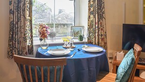 A dining area with a table set for two, a vase with flowers, and a window with curtains. - 2 bedroom accommodation in Middlesmoor, near Pateley Bridge (Middlesmoor, near Pateley Bridge)