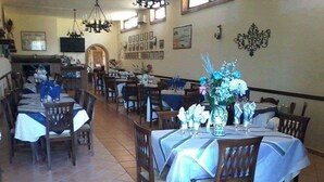 Un restaurante con varias mesas y sillas, piso de baldosas y decoración en las paredes.