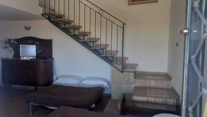 Un dormitorio con una cama, un escritorio con una computadora, un aparador y una escalera.
