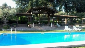 Una piscina con pérgola y sillas de descanso.