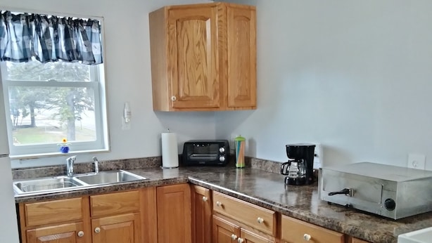 A kitchen with wooden cabinets, a granite countertop, a toaster, and a coffee maker.