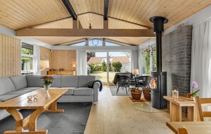 A cozy living room with a wooden ceiling, a sofa, a table, and a fireplace. - Beautiful home in Dronningmølle (Dronningmølle)