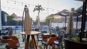 An outdoor seating area with tables and chairs, a pool, and umbrellas. - The Panama  (Abuja)