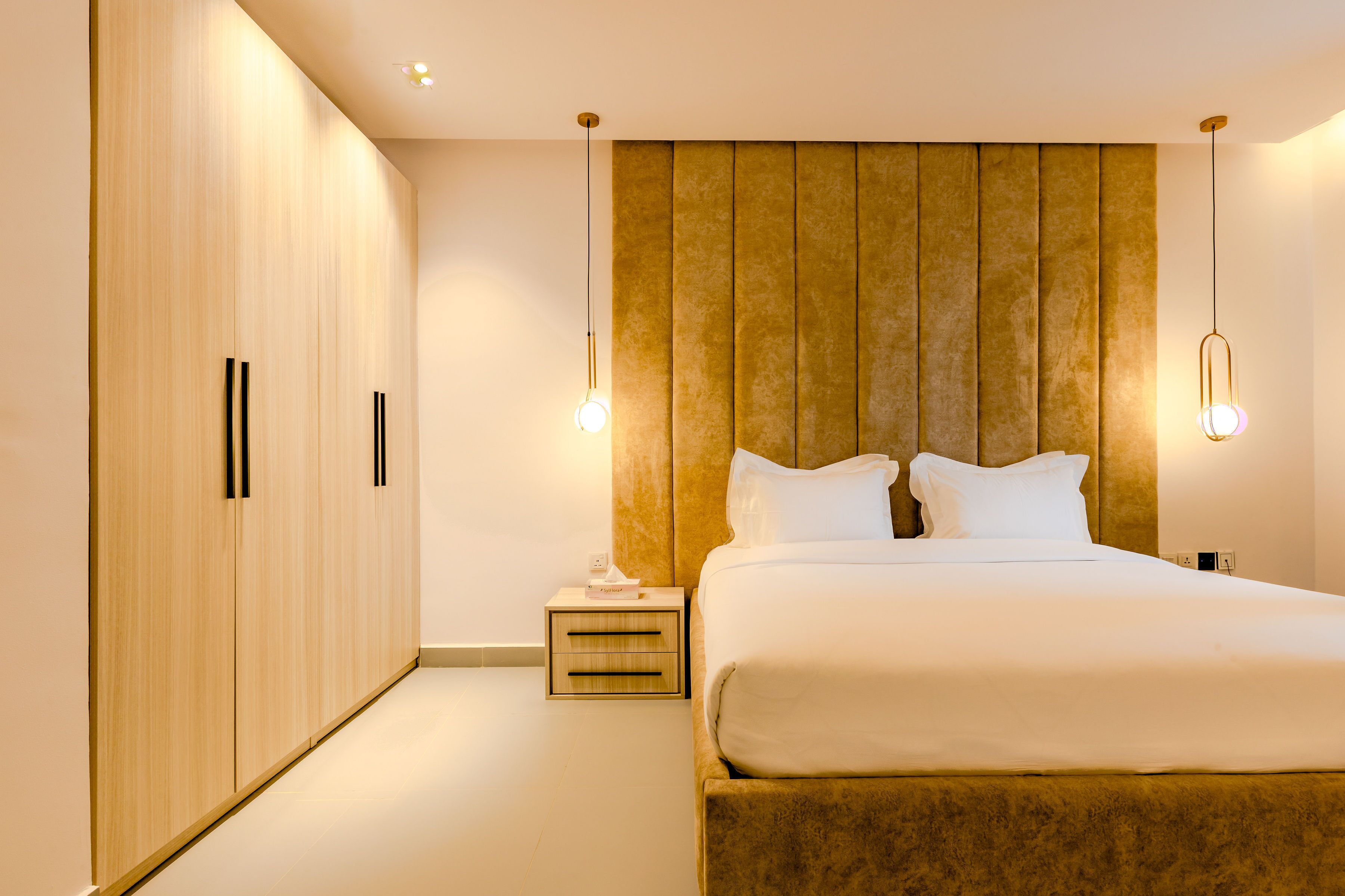 Une chambre à coucher moderne avec un grand lit, une armoire en bois et des lampes de chevet.