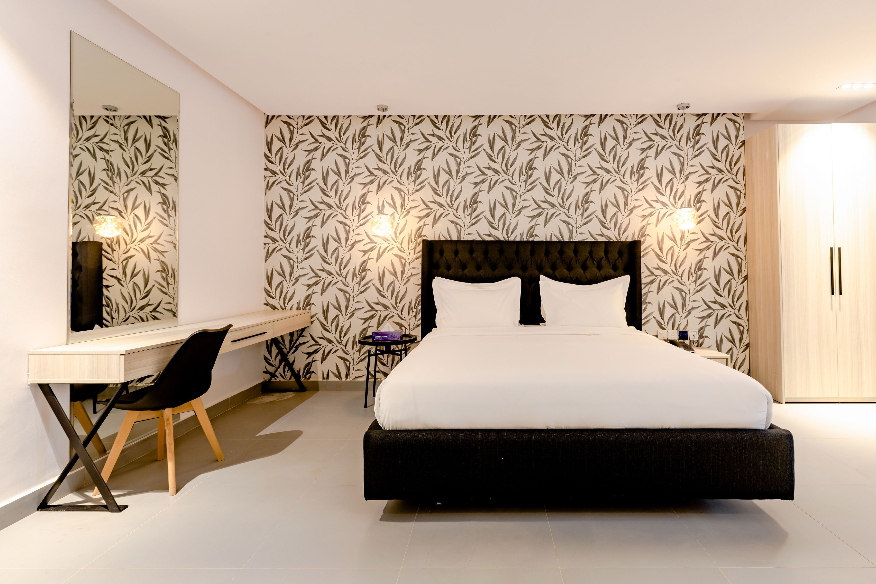 A modern bedroom with a large bed, a desk, and a chair.