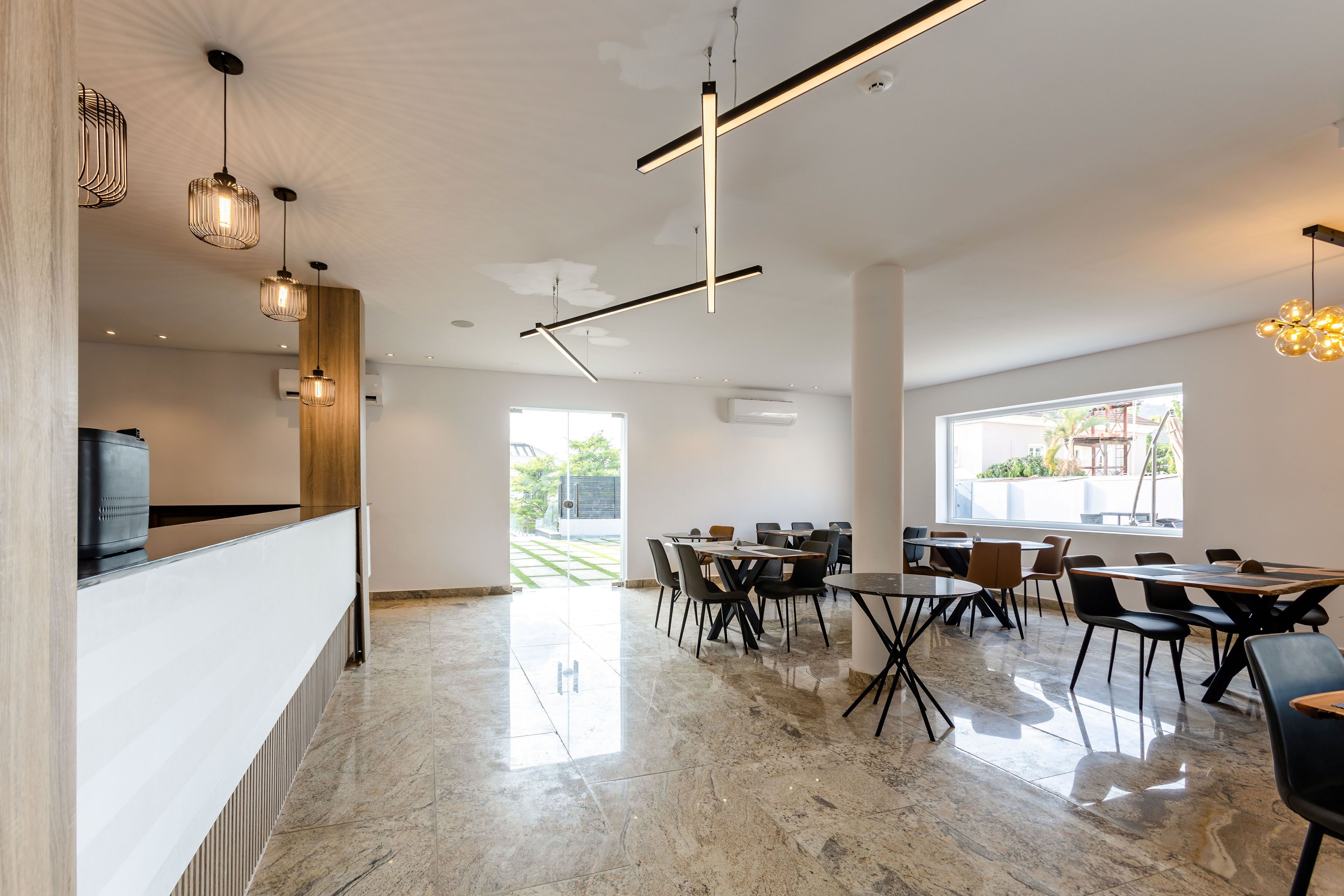 Een moderne eetruimte met een lange tafel en stoelen, een keukenwerkblad en hanglampen.