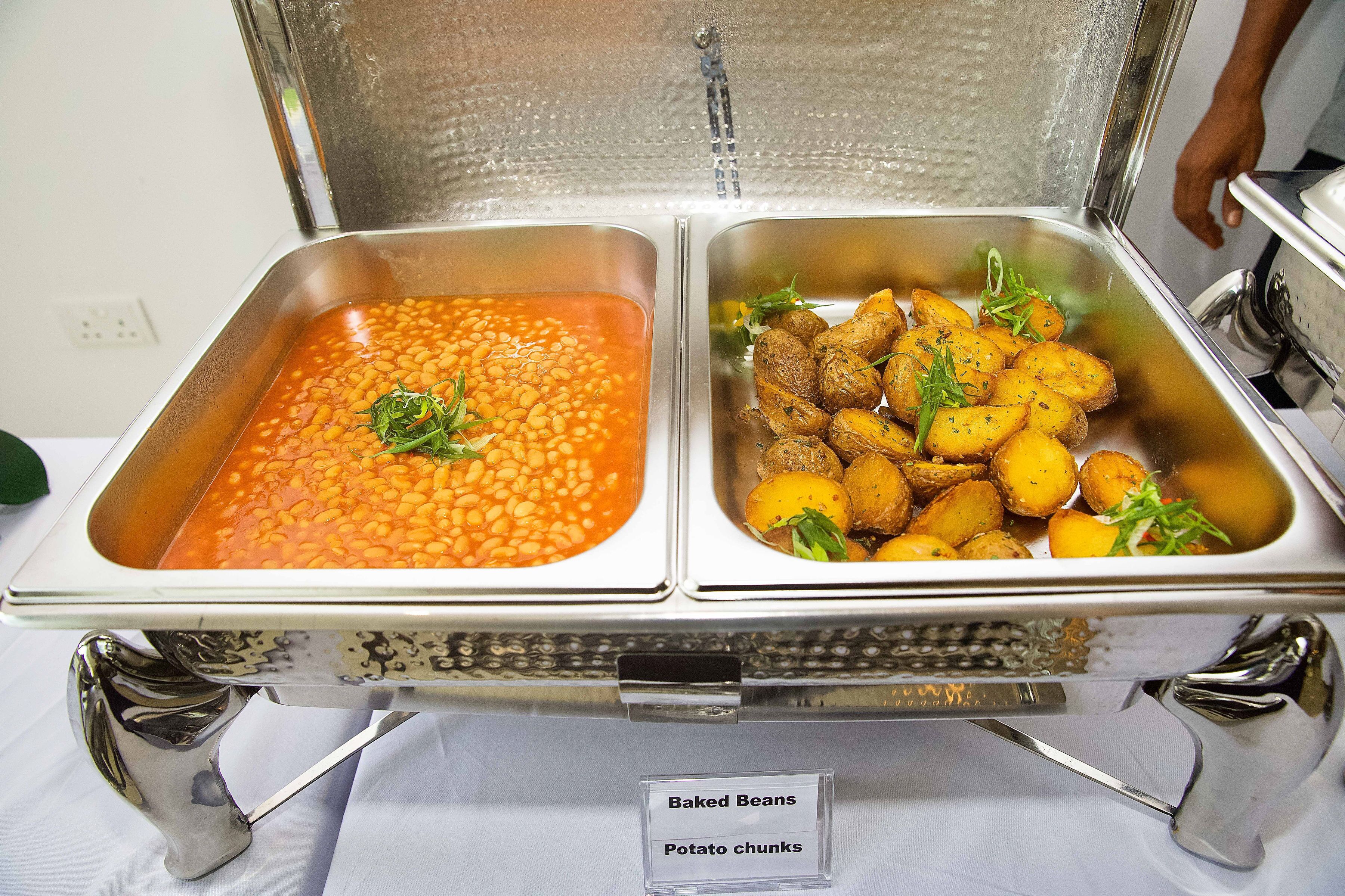 A buffet with baked beans and potato chunks.