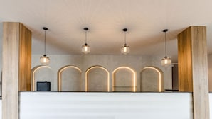 A reception area with a wooden reception desk, three pendant lights, and a modern ceiling design. - The Panama  (Abuja)