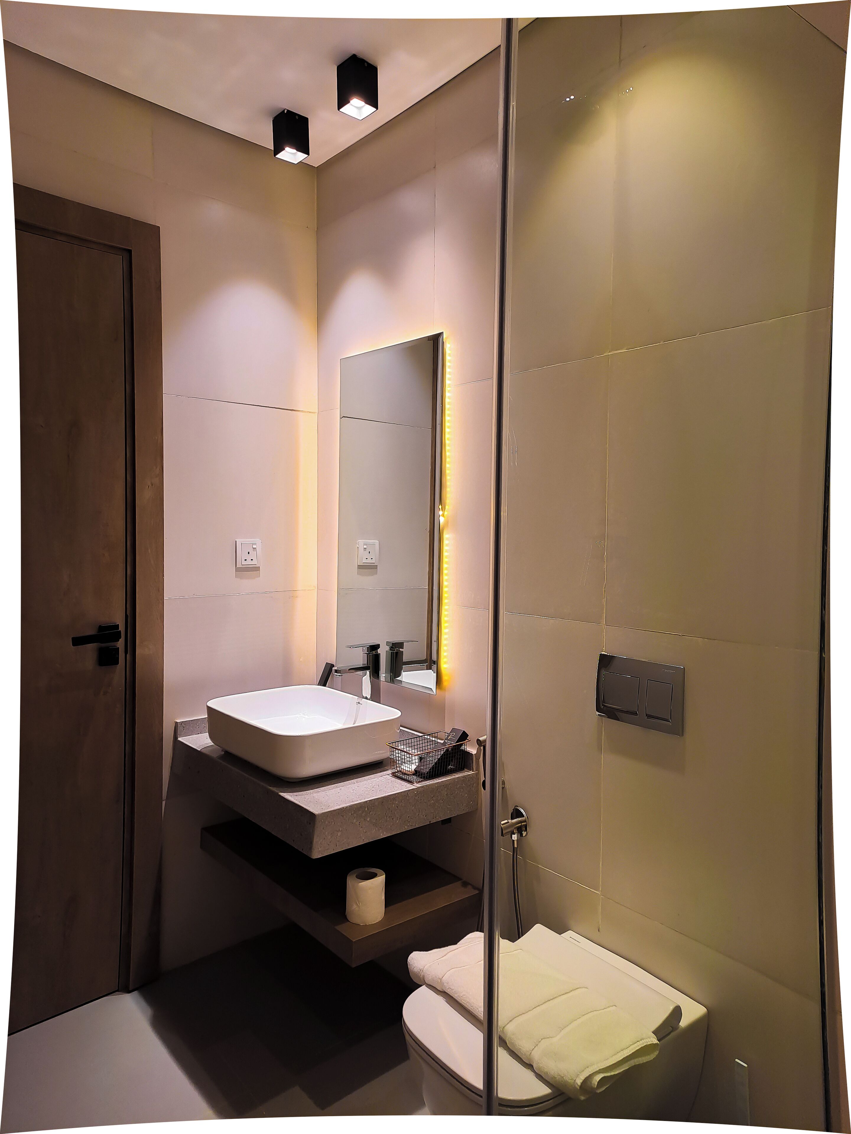 A modern bathroom with a large mirror, a sink, and a toilet.