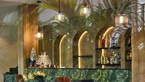 A bar area with a tropical theme, featuring a counter, bar stools, and a display of bottles. - The Panama  (Abuja)
