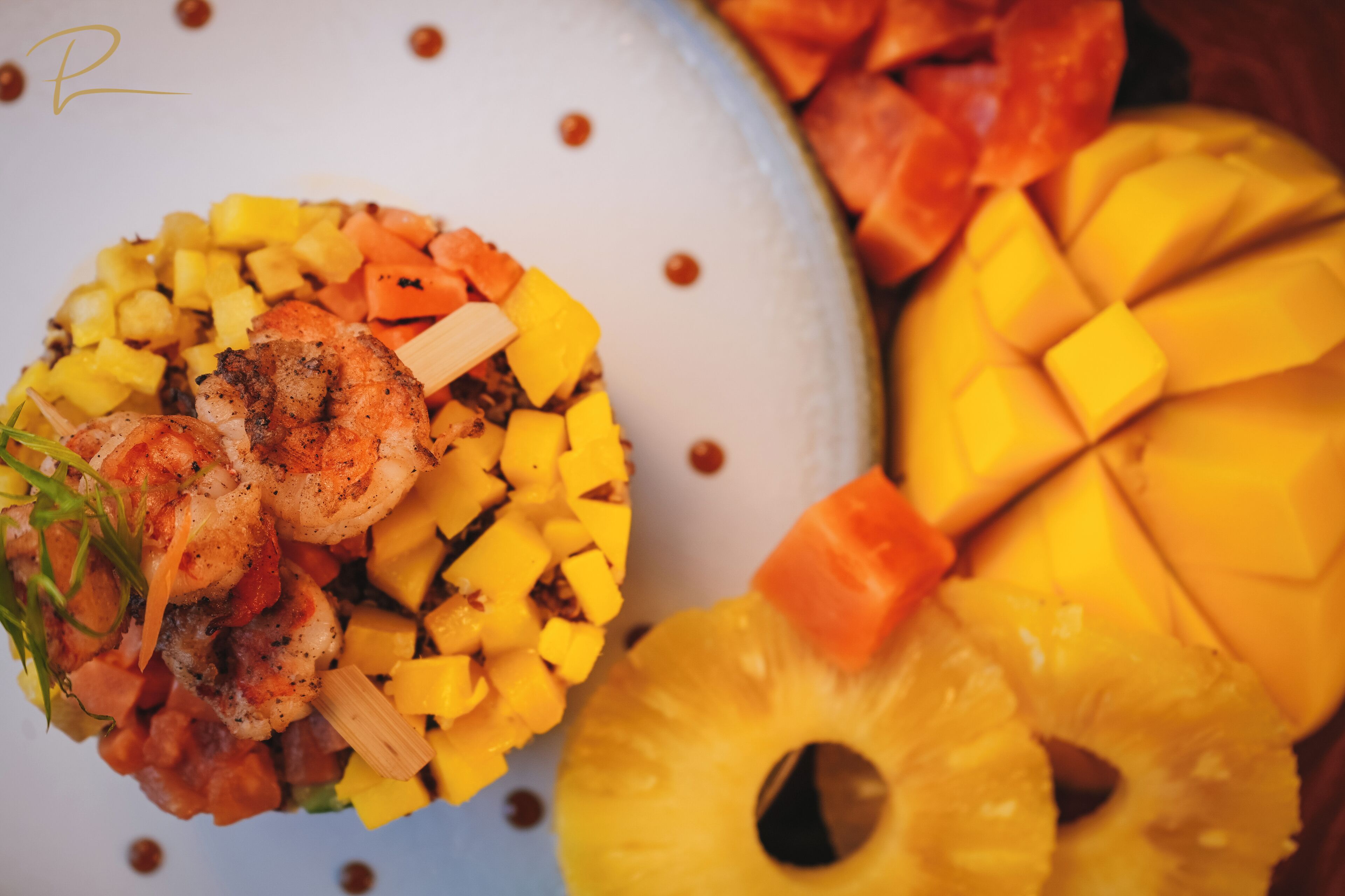 A plate with grilled shrimp, diced mango, and pineapple slices.