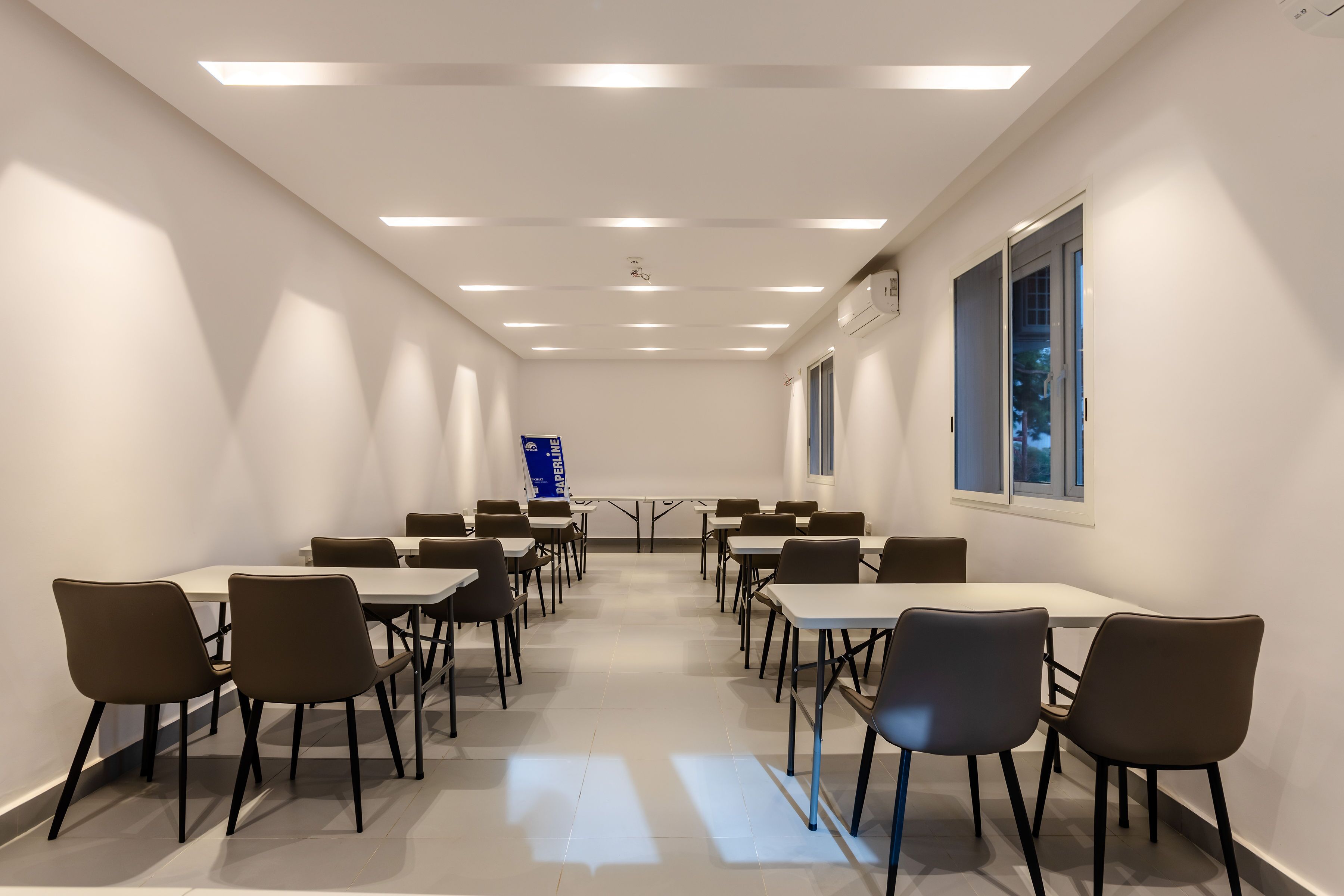A conference room with tables and chairs, a blue banner, and windows with views.