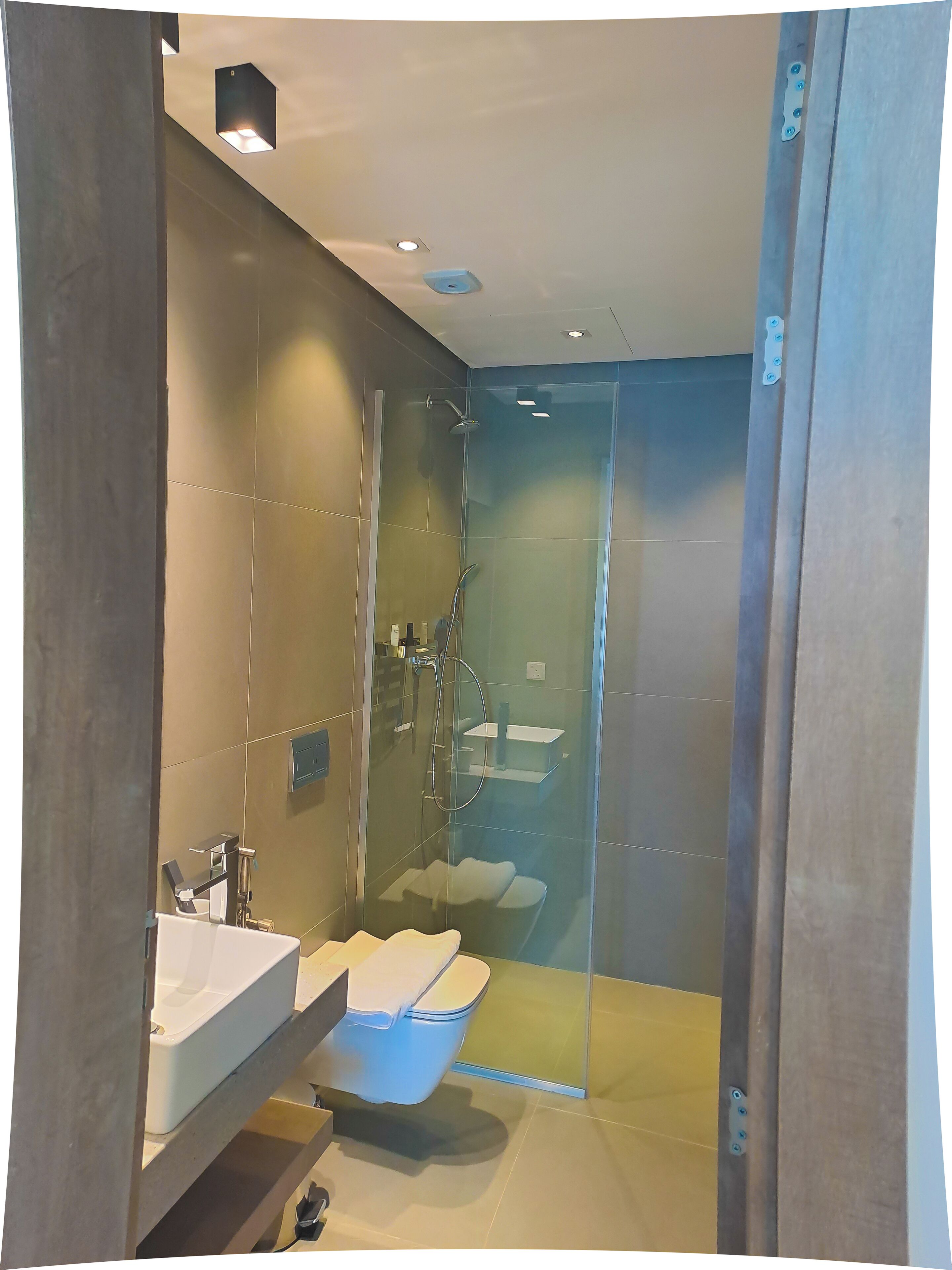 Ein modernes Badezimmer mit einer Duschkabine, einem weißen Waschbecken und einer Toilette.