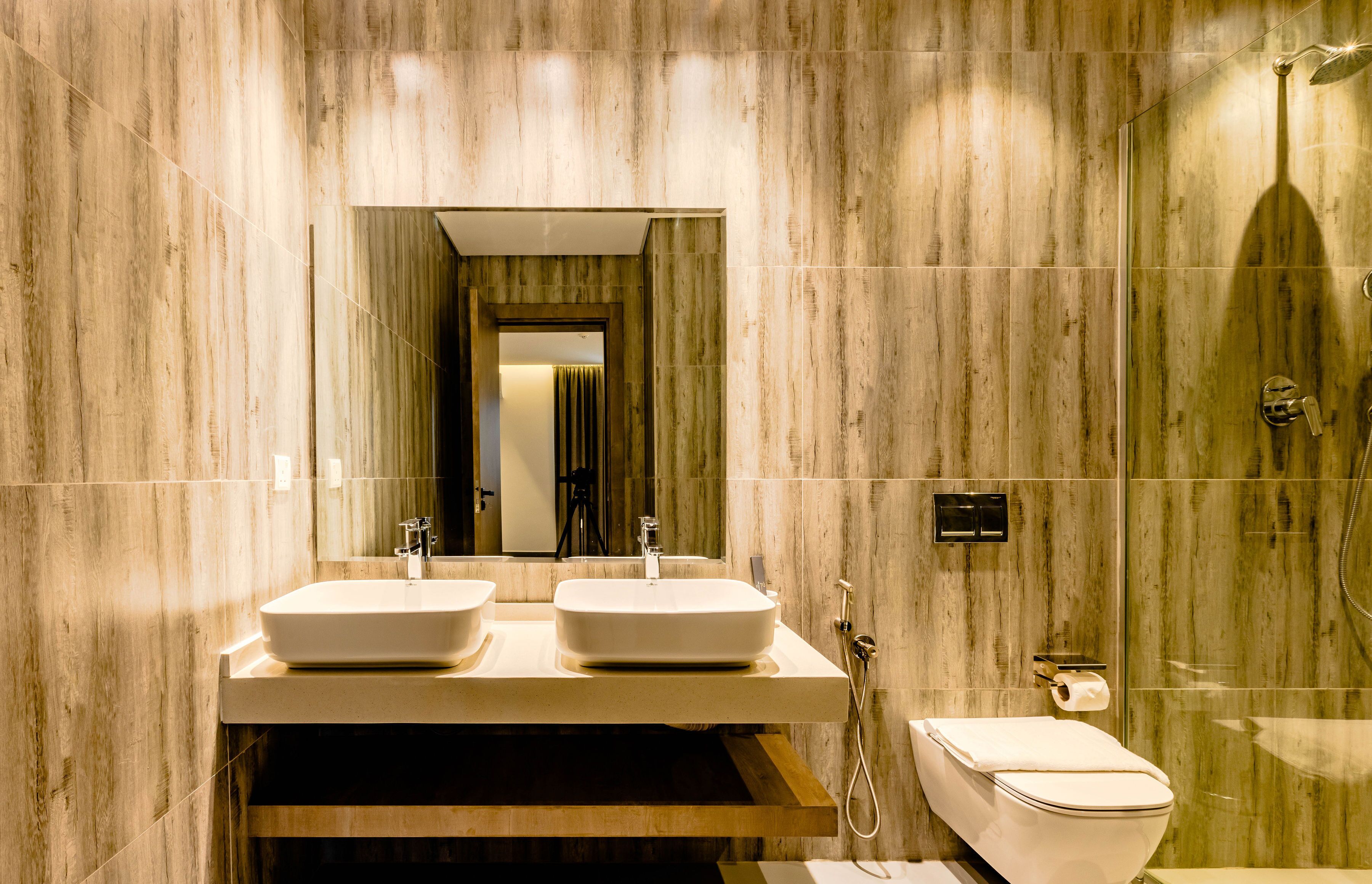 A modern bathroom with two sinks, a toilet, and a shower.